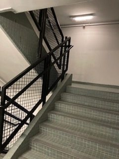 Photo of HKUST Library back stairwell - picture of grey empty stair well with metal balustrades, tile stairs, and concrete walls