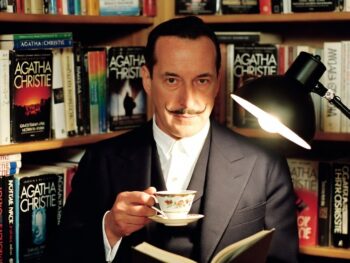 AI-Generated Image of Poirot holding a cup of tea, sitting in front of a shelf of Agatha Christie's work