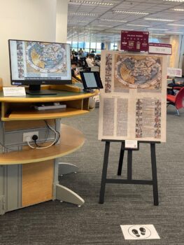 Computer monitor displaying project video and an easel showing the two sides of the 1493 map of the "Second Stage of the Wolrd" from the Nuremberg Chronicle