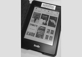 photo of a kindle paperwhite open with thumbnails of some titles on screen