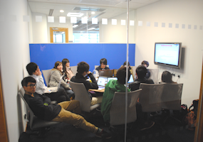 photo of several students inside a group study room in the Learning Commons (LC)
