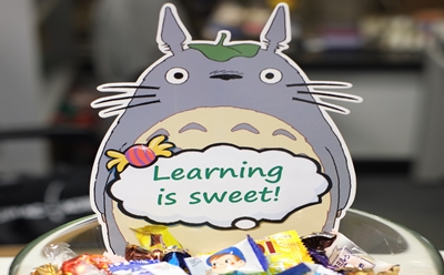 Photo of bowl of candy with a label of a Totoro image with "Learning is Sweet" slogan